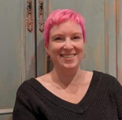 A smiling woman with pink hair
