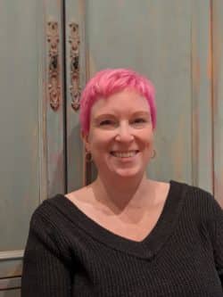 A smiling woman with pink hair