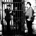 A man standing in front of two people in a cage